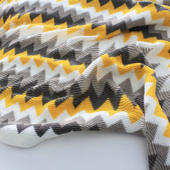 Vibrant zigzag patterned blanket in yellow, gray, and white, showcasing affordable quality homewares perfect for adding style to value furniture.