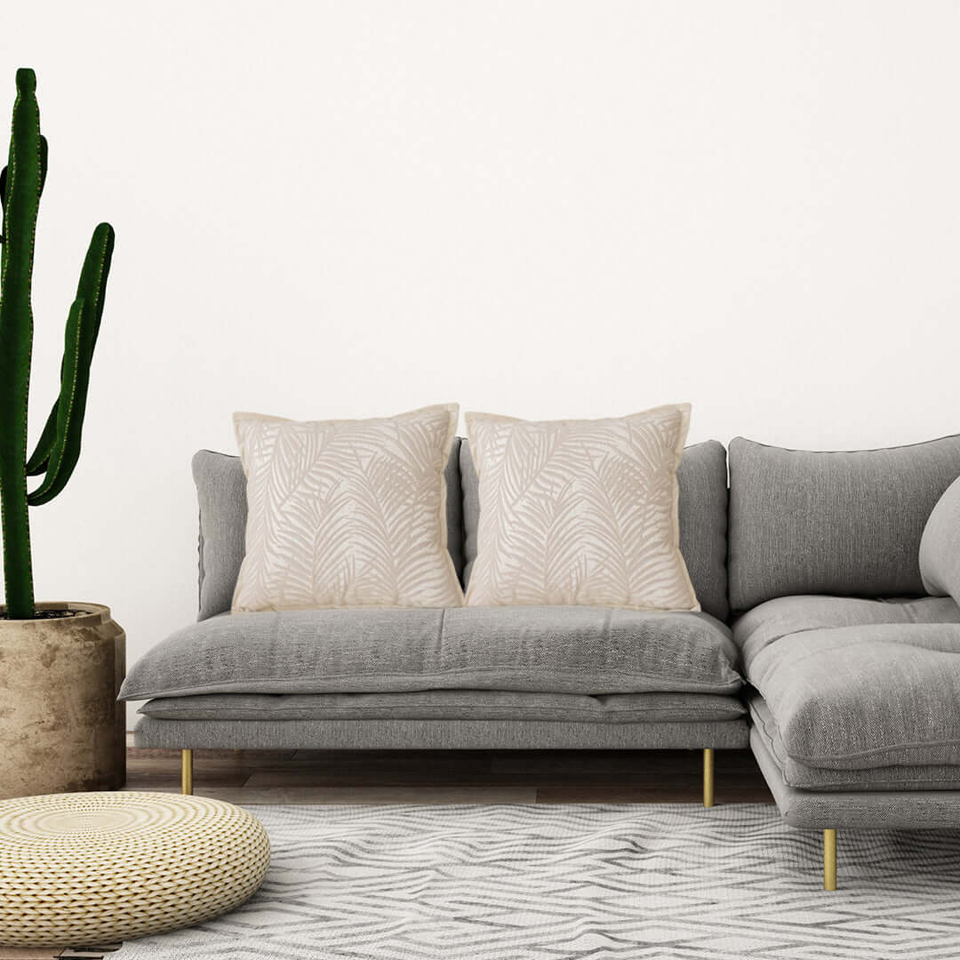 Modern grey sofa with white pillows in stylish living room with cactus and pouf; affordable homewares and quality value furniture.