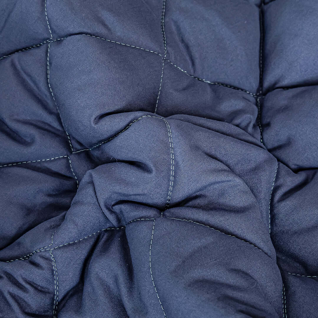 "Close-up of affordable, quality blue quilted homeware fabric with detailed stitching, offering value and comfort."