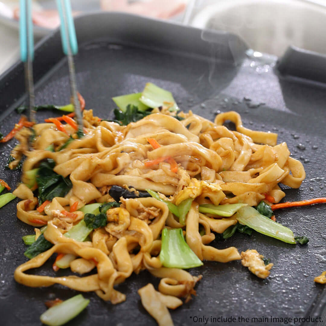 Cooking stir-fried noodles with vegetables on a griddle