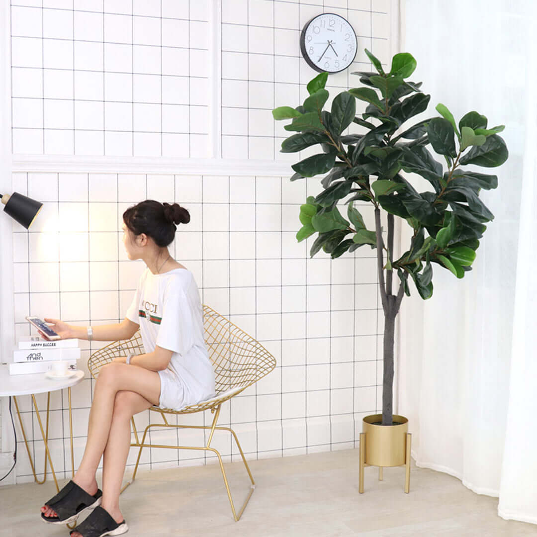 Woman sitting on modern wire chair next to decorative indoor plant in stylish living space with affordable homewares and quality value furniture.