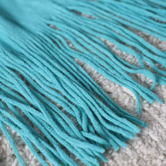 Close-up of turquoise fringed fabric on a textured surface, representing affordable and quality homewares with value furniture.