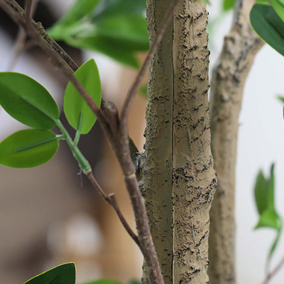 Close-up of a realistic artificial tree trunk and green leaves, showcasing quality craftsmanship for home decor.