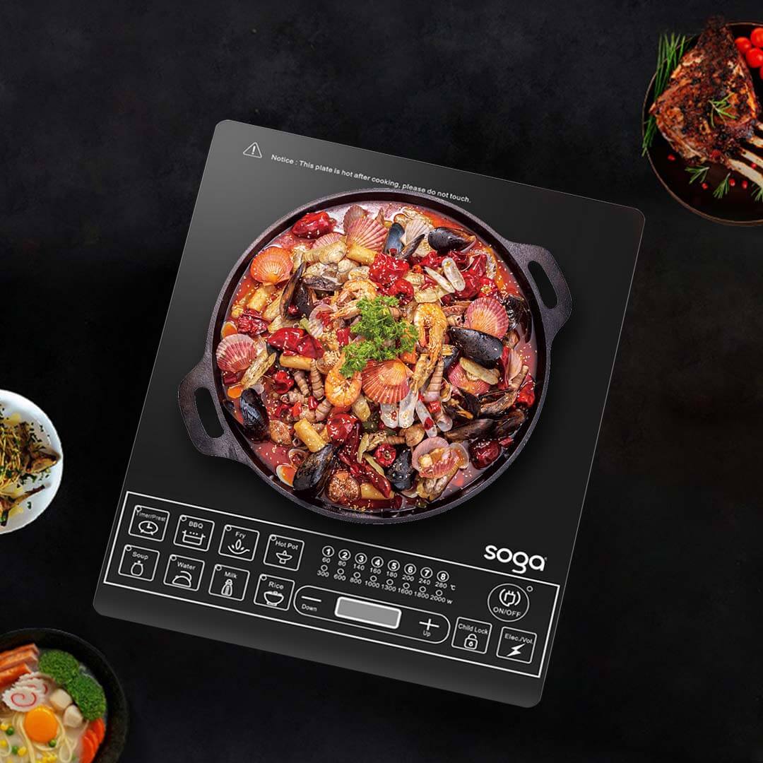 Induction cooktop with a pot of mixed seafood stew, surrounded by various dishes, by Soga.