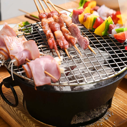 Skewers of meat and vegetables grilling on a small, portable barbecue grill