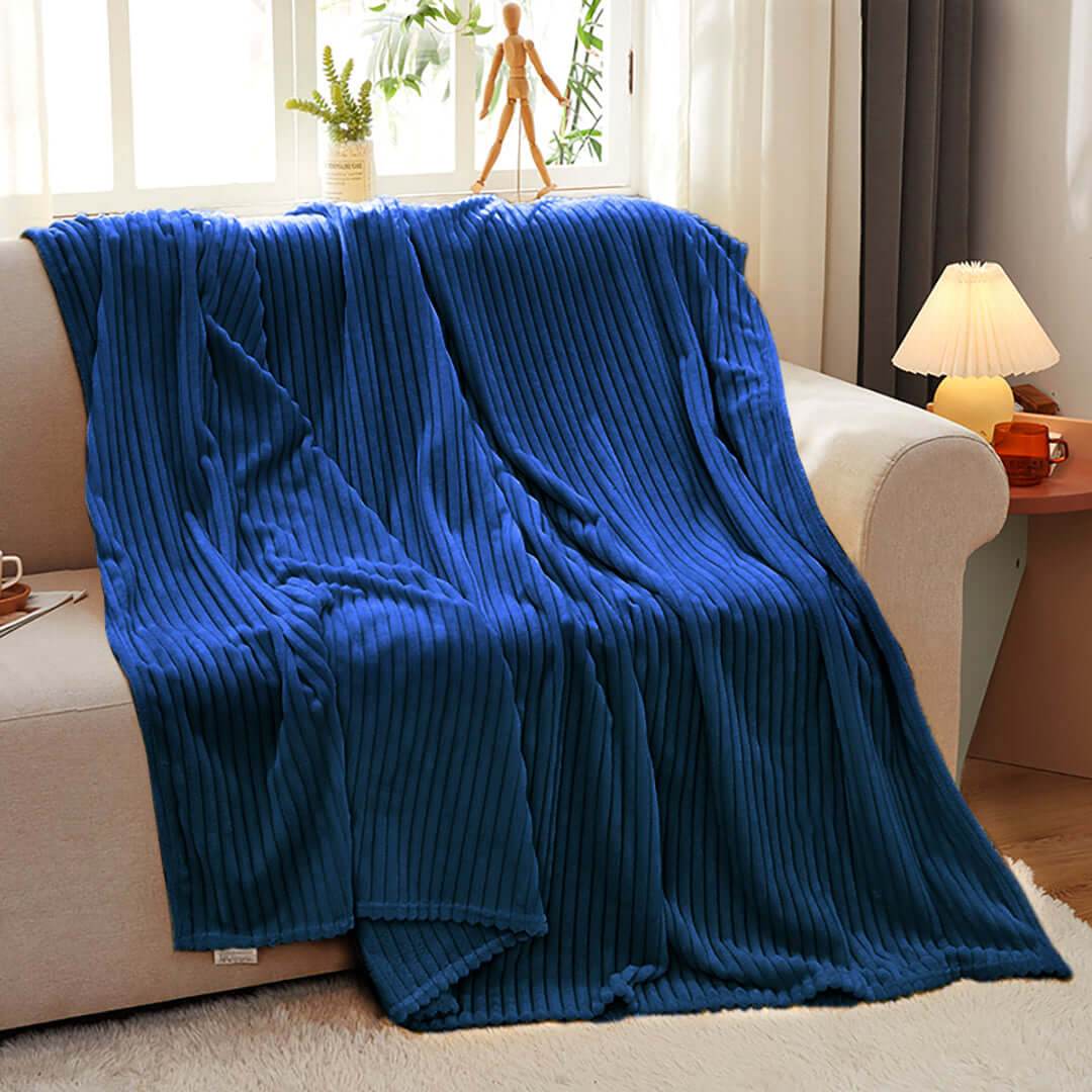 Royal blue rib-knit blanket draped over a beige sofa, showcasing affordable quality homewares and value furniture.