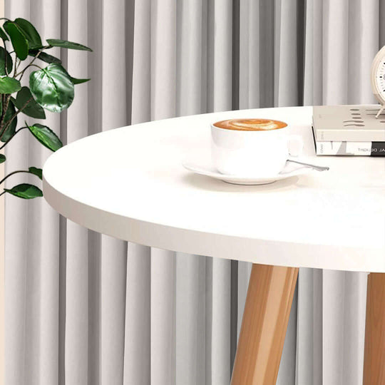 Minimalist round white table with coffee cup and book, beside a green plant, showcasing affordable, quality homewares and value furniture.