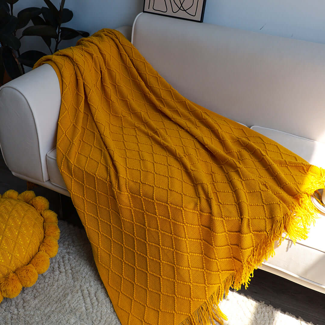 Affordable quality homewares - cozy mustard yellow throw blanket draped over a value furniture sofa in a modern living room.