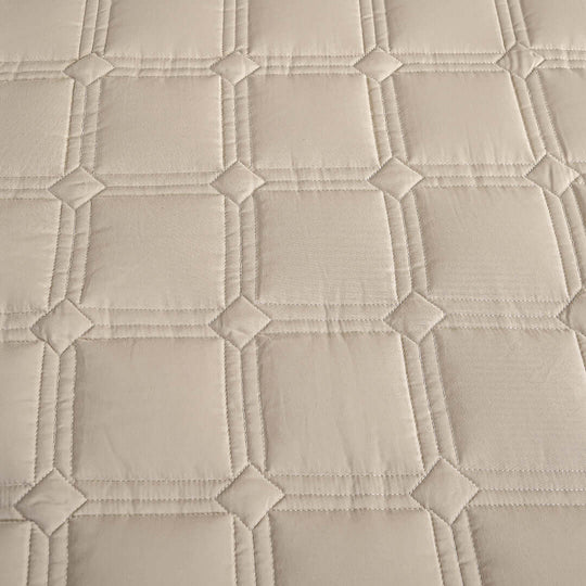 Textured beige fabric with a quilted square pattern.