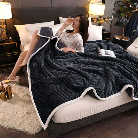 Woman enjoying a cozy affordable blanket on a bed with quality homewares and value furniture in a stylish bedroom setting.