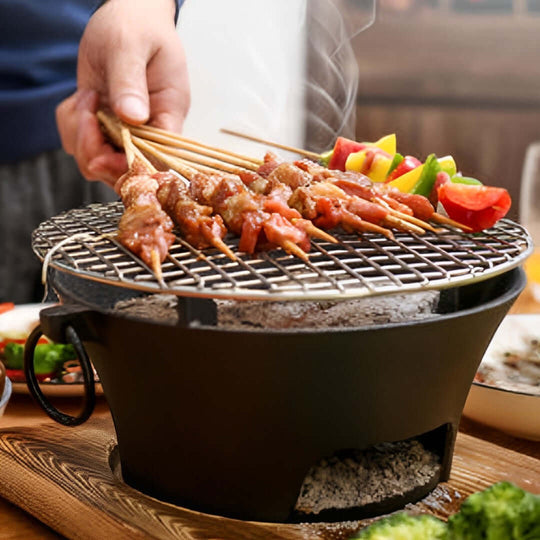 Man grilling skewers on a portable charcoal grill with vegetables and meat in a cozy home setting