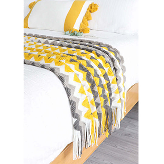 Modern bed with yellow and gray patterned throw blanket and decorative pillows, showcasing affordable quality homewares and value furniture.