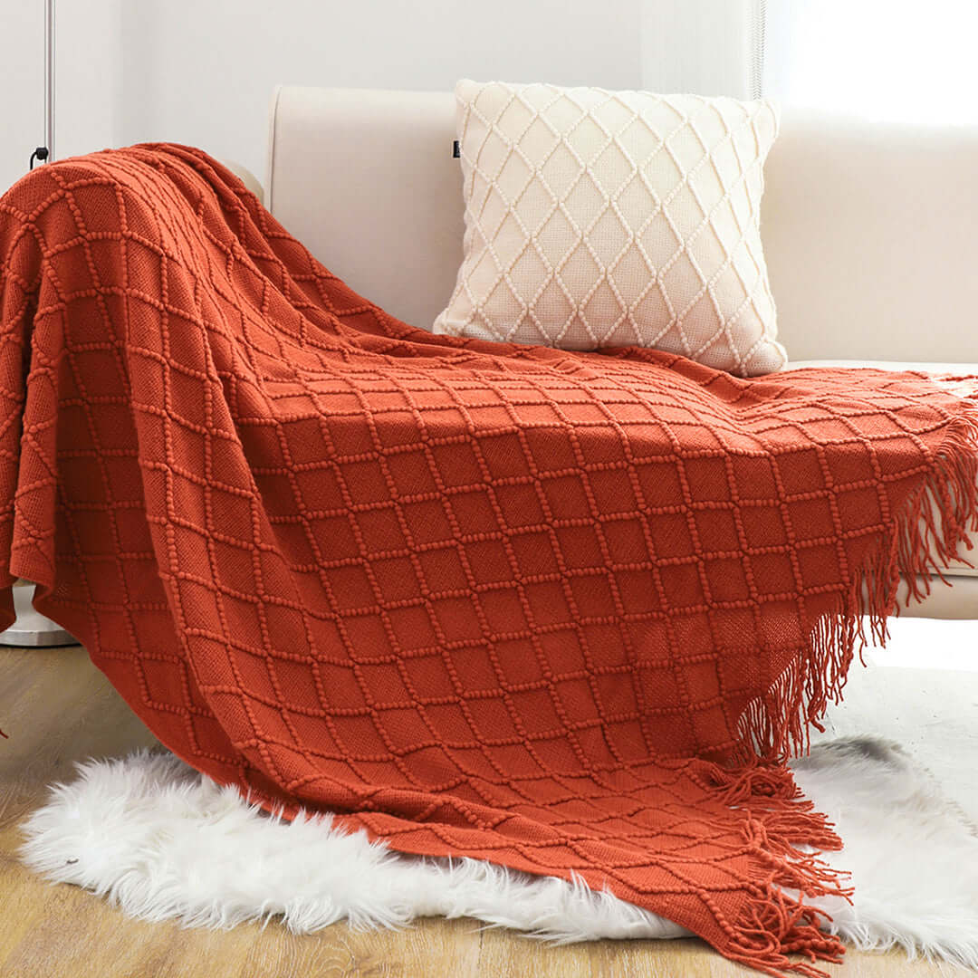 Affordable quality homewares - red textured throw blanket and white cushion on sofa demonstrating value furniture accessories.