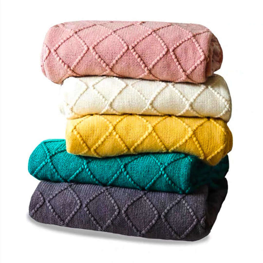 Stack of colorful, textured blankets offering affordable homewares. High-quality value furniture items.