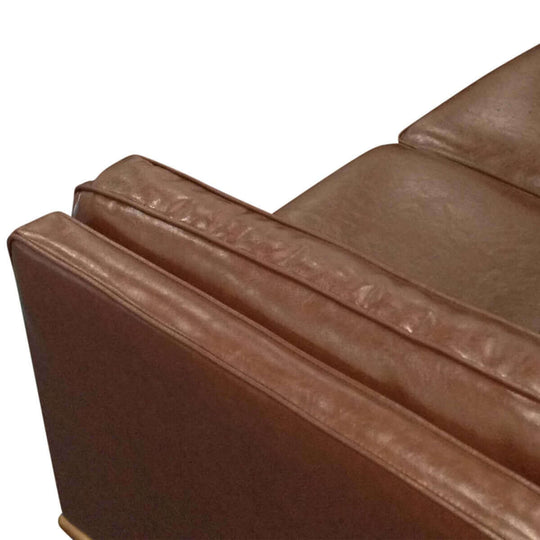 Close-up of double layered brown faux leather cushion on modern 2 seater sofa with wooden frame. Ideal for families with children.