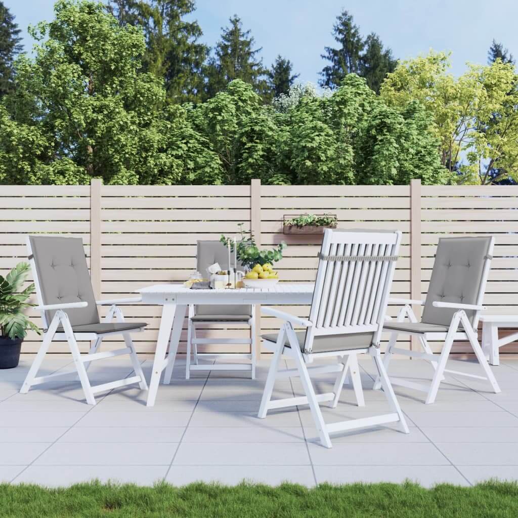 Outdoor patio with white furniture set featuring grey highback chair cushions, placed on a tiled terrace against a backdrop of lush greenery.