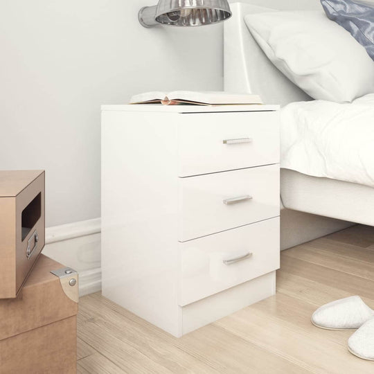 White engineered wood bedside cabinet with three drawers, placed next to a bed, offering affordable quality storage for magazines and small items.