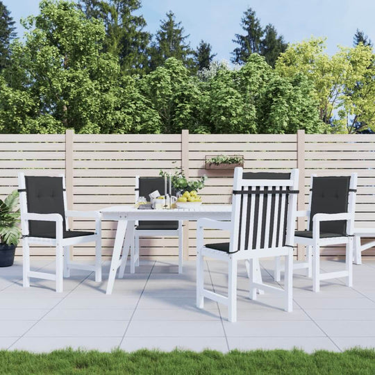 Outdoor patio set with black cushioned lowback chairs and a white table against a wooden fence backdrop with greenery.