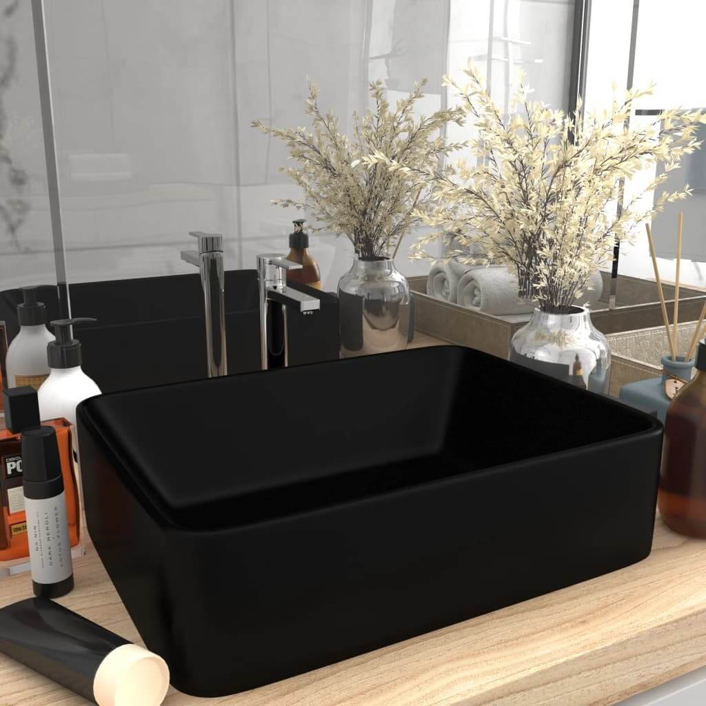 Luxury matt black ceramic wash basin 41x30x12 cm placed on a bathroom console surrounded by toiletries and decor.