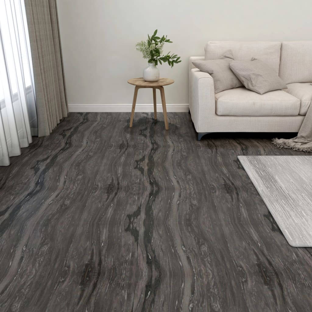 Dark grey self-adhesive PVC flooring planks in a modern living room with a white sofa and a wooden side table.