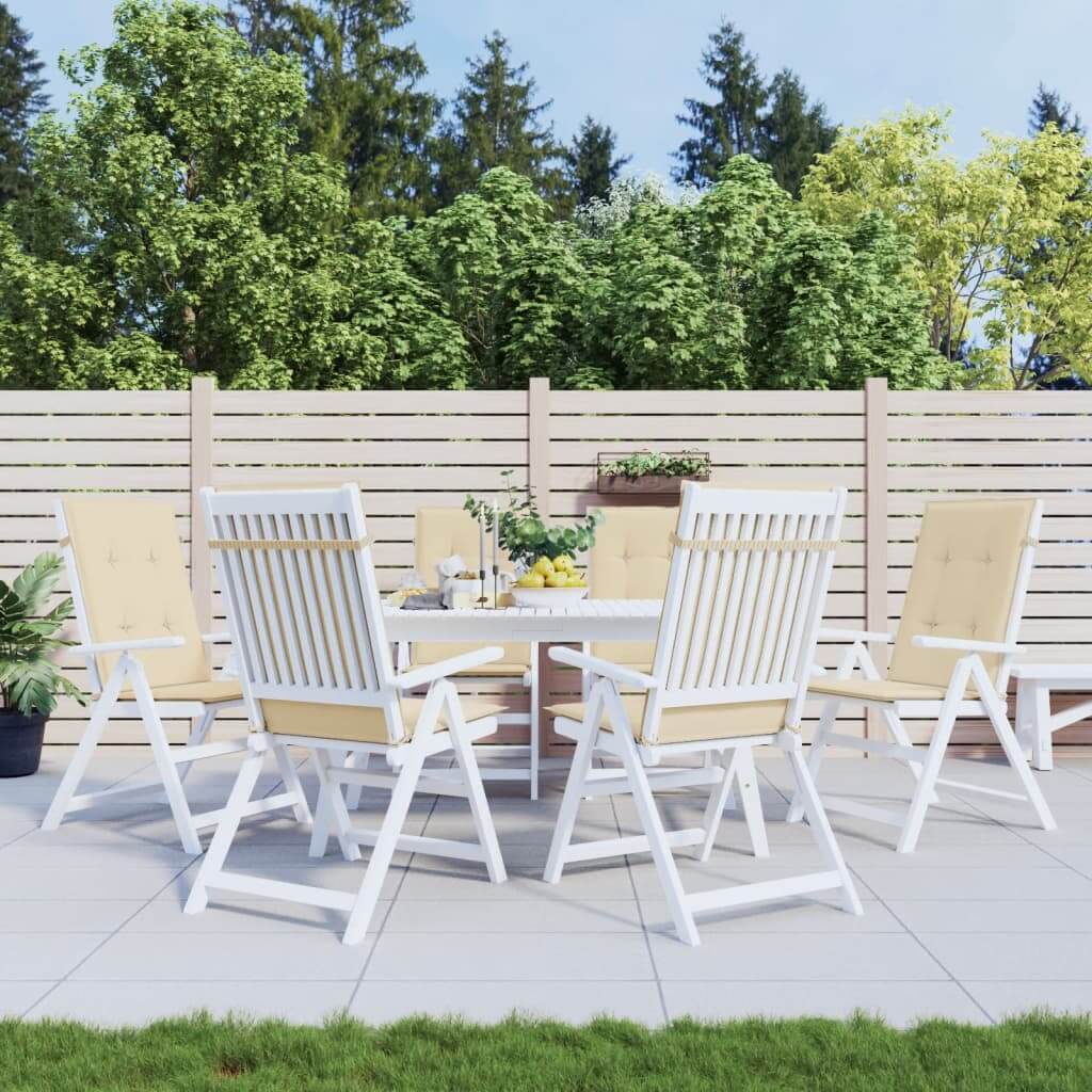 Beige garden highback chair cushions on patio furniture set with green background and wooden fence.