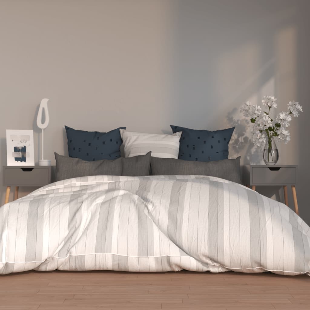 Modern bedroom setup featuring grey bedside cabinets, stylish blue and grey pillows, white and grey bed linens, and decorative items on the cabinets.