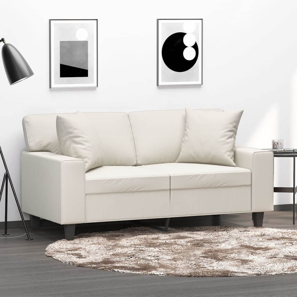 Cream throw pillows on a stylish sofa in a modern living room with minimalist decor and wall art.