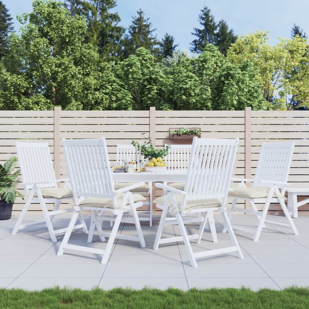 Outdoor dining area with white chairs and cream white chair cushions, surrounded by greenery and a wooden fence, showcasing affordable quality.