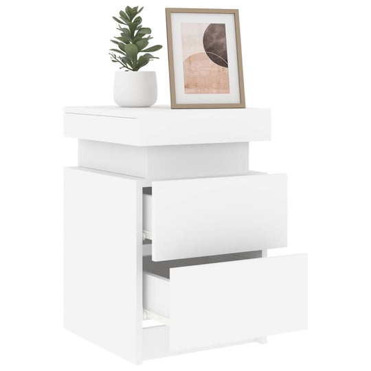 Affordable white bedside cabinet with LED lights, open drawers, and decor items on top, offering quality storage options for bedrooms.