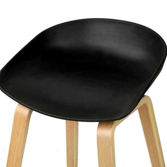 Close-up of a black PP plastic seat on a Bentwood bar stool with natural wooden legs, ideal for affordable and stylish dining.