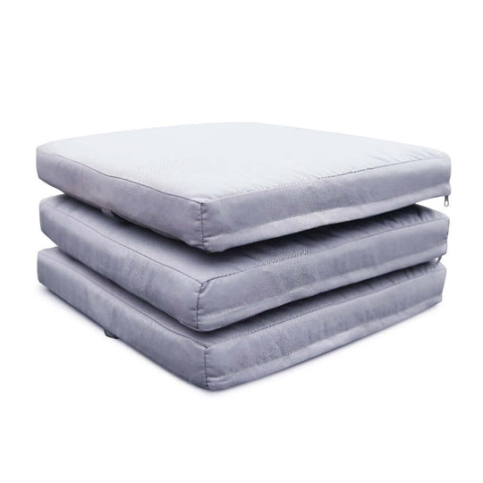 Stack of three soft gray outdoor seat cushions for patio furniture.