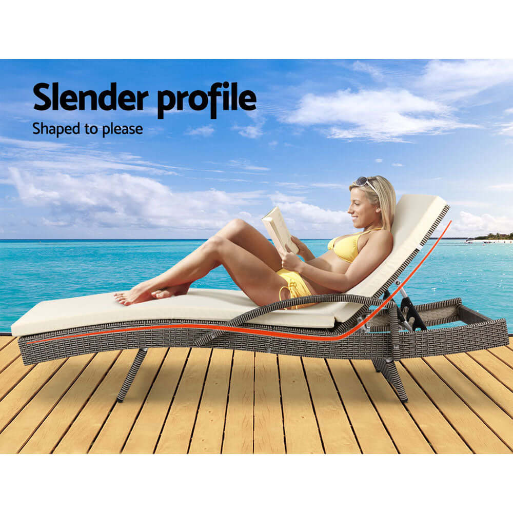 Woman relaxing on Gardeon sun lounge by the beach, featured with grey and beige cushions for ultimate comfort.