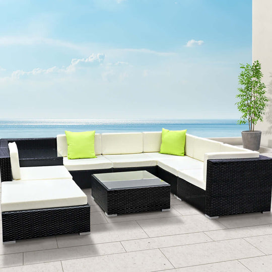 Gardeon 9-piece outdoor wicker sofa set with vibrant green cushions by the sea.