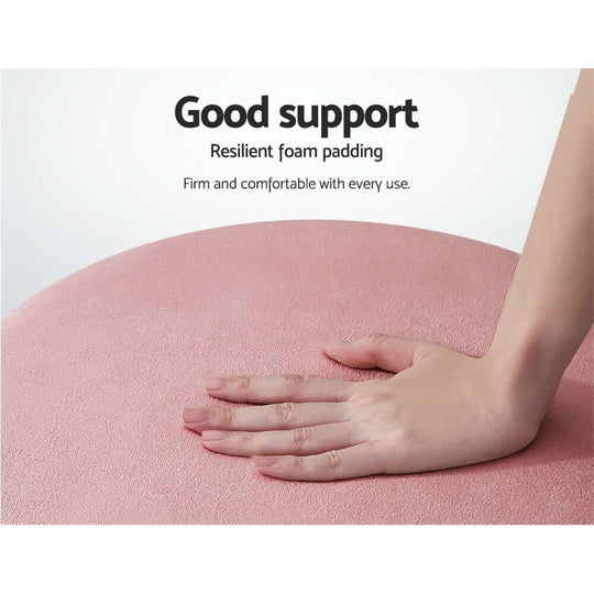 Close-up of a hand pressing on a pink velvet ottoman, showcasing firm support and comfortable foam padding.