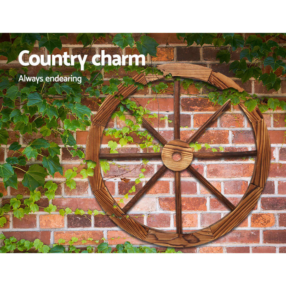 Gardeon Wooden Wagon Wheel on brick wall with greenery, showcasing rustic charm for affordable home décor.