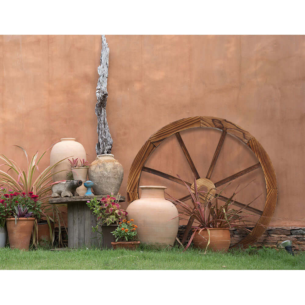 Rustic Gardeon Wooden Wagon Wheel used in garden decor, surrounded by clay pots and plants for a vintage aesthetic.