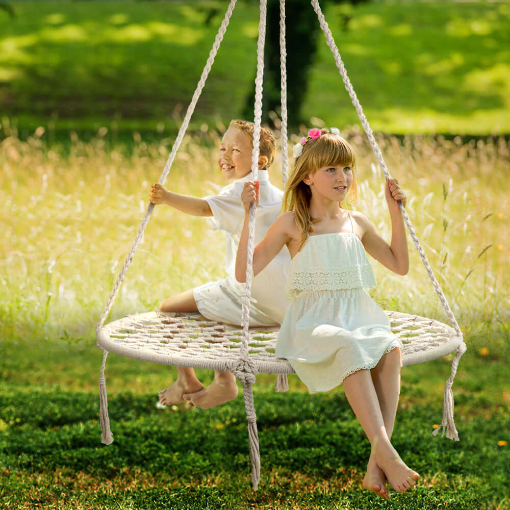 Kids enjoying the Gardeon Hammock Chair outdoor swing in a sunny field, perfect for relaxation and fun.