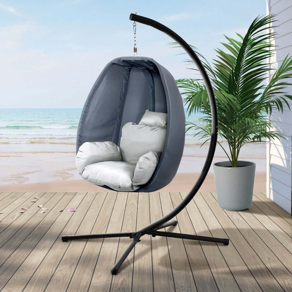 Gardeon outdoor egg swing chair in grey on patio by the beach, offering affordable luxury and comfort.