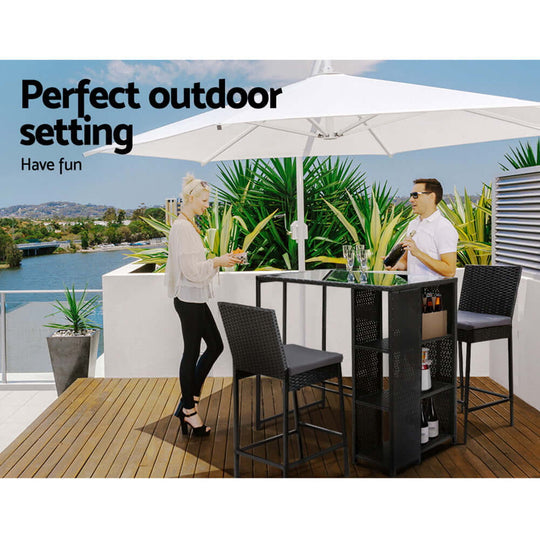 Chic outdoor bar set featuring wicker stools and a table with umbrella, perfect for summer gatherings.