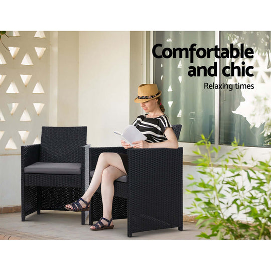 Woman reading in stylish black rattan chairs, enjoying a relaxing outdoor moment under sunlight.