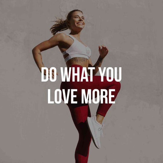 Fit woman in athletic wear jumping joyfully with motivational text "Do What You Love More" for fitness inspiration.