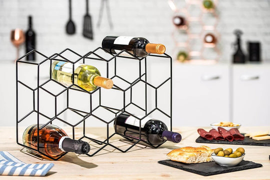 Stylish freestanding modern metal wine rack holding four bottles, complemented by a selection of gourmet snacks and tableware.