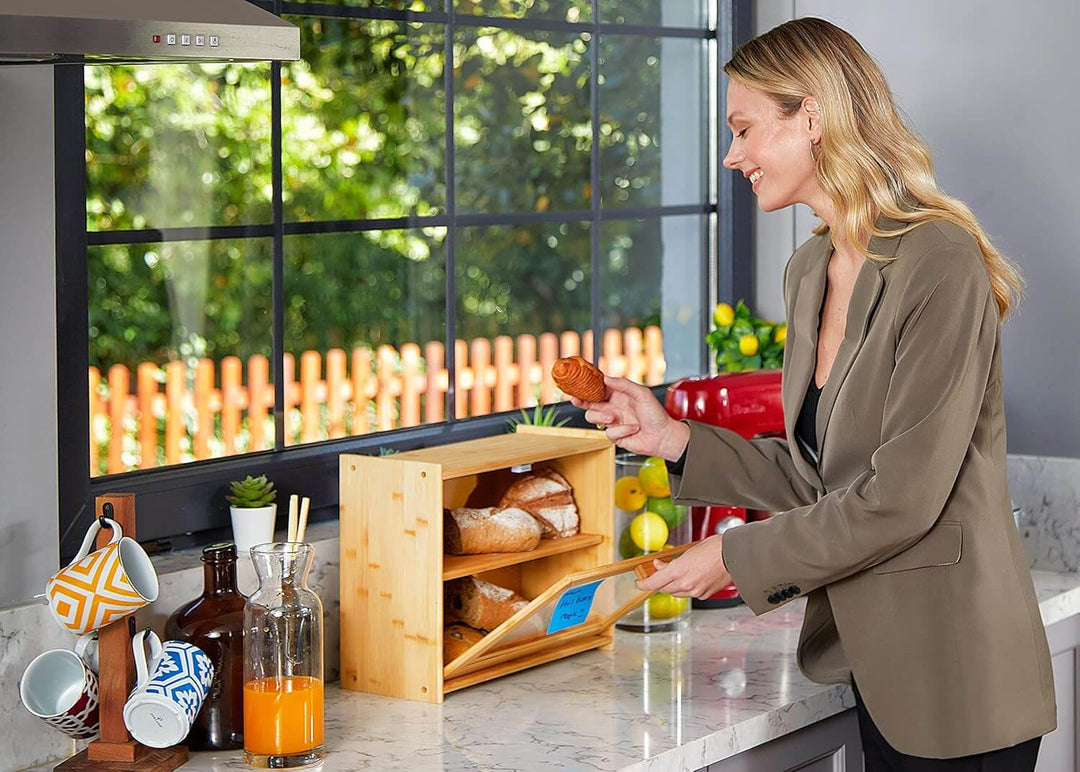 Woman placing a cookie in a double layer bamboo bread box on a kitchen counter, showcasing spacious storage and modern design.