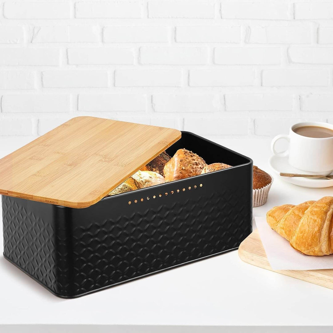 Stylish black bread bin with bamboo lid, perfect for storing baked goods on kitchen countertop.