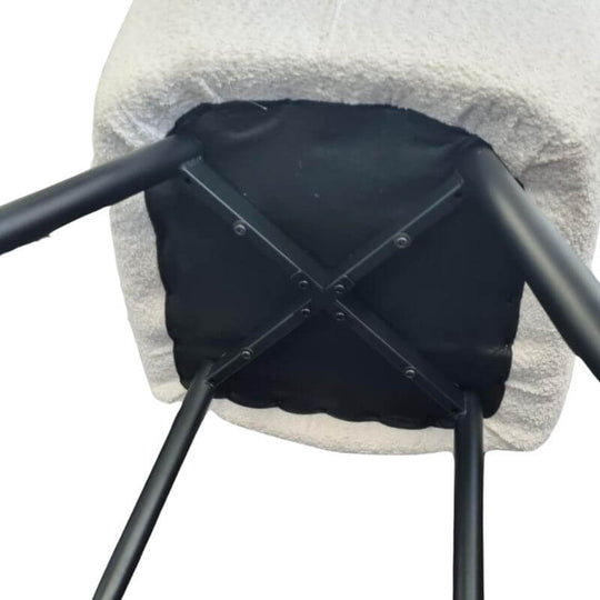 Underside view of a Neo Softy light grey dining chair, showcasing black metal legs and sturdy construction.