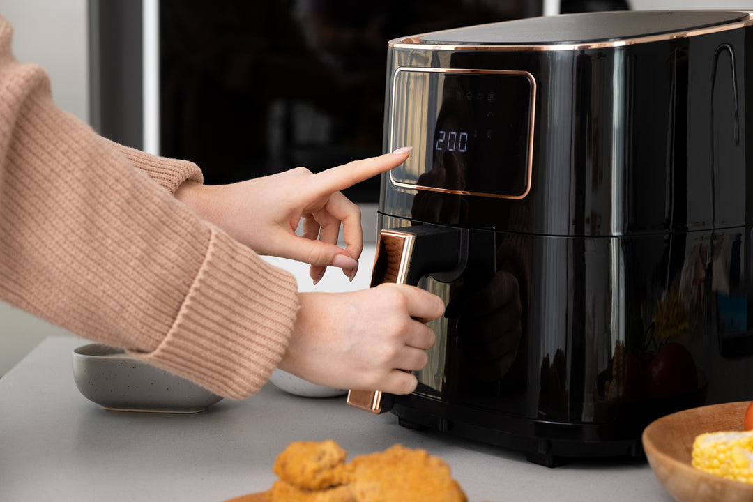 Person using a black digital air fryer set to 200C, with golden brown chicken pieces and corn on the table