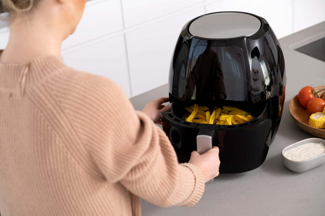 Woman using 8L digital air fryer to cook french fries in a modern kitchen