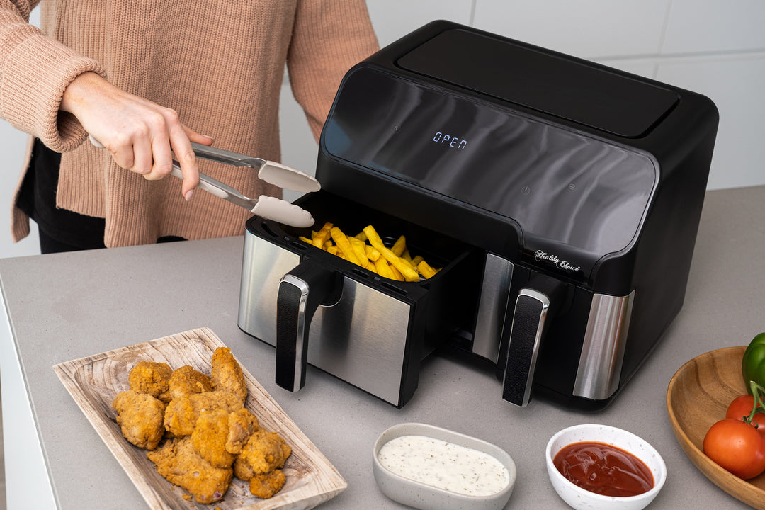 Person using 10L Digital Dual Zone Air Fryer to cook fries and chicken wings, showcasing dual temperature control and quality cooking.