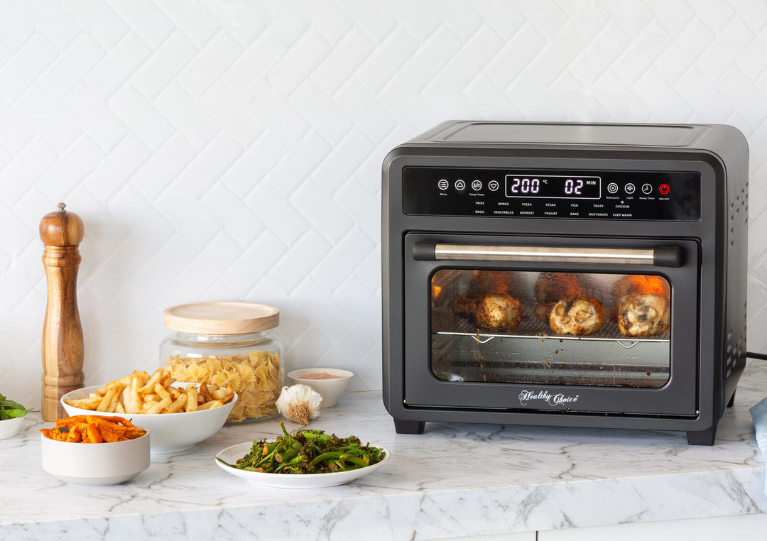 23L Digital Air Fryer Convection Oven with rotisserie chicken and side dishes on a kitchen counter, showcasing its 12 cooking programs.