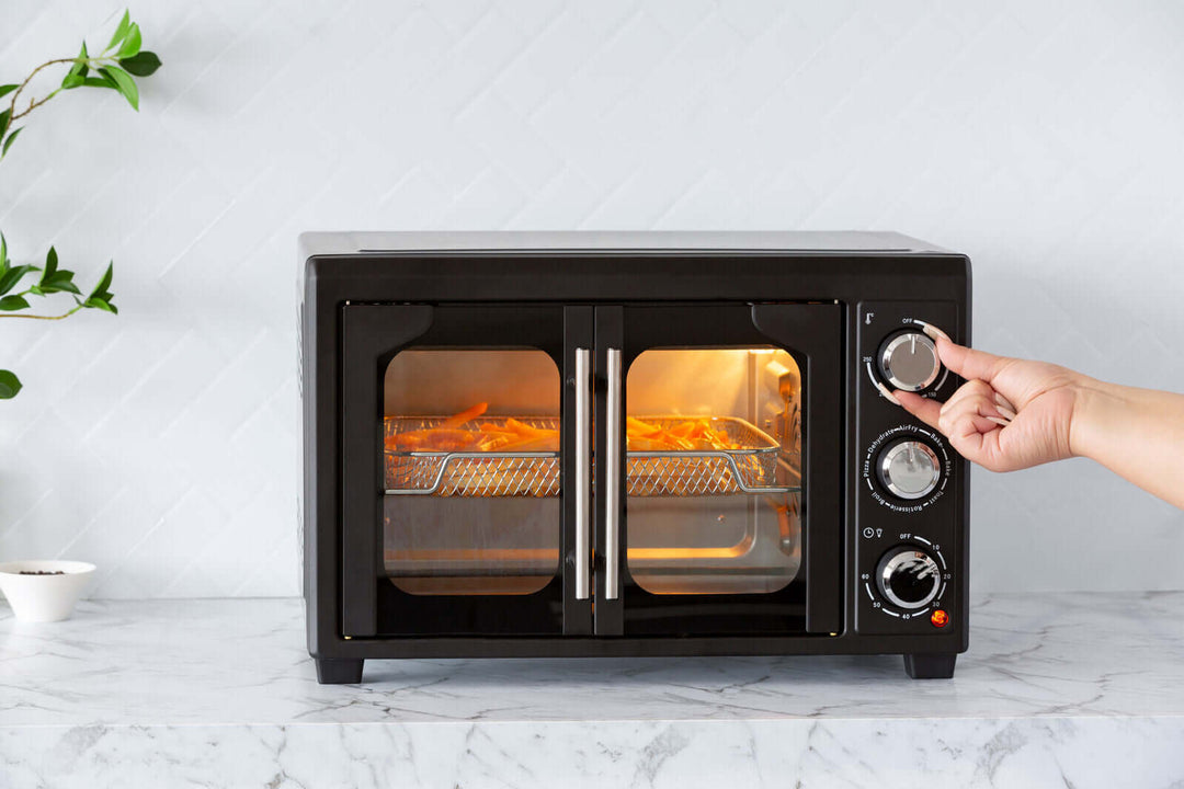 Affordable 30L air fryer convection oven with rotisserie, user adjusting settings for perfect cooking results.